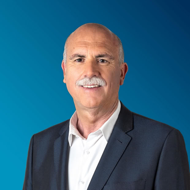 Two happy store owners smiling while wearing aprons in a local grocery store.